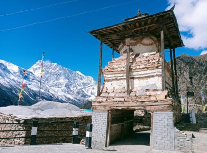 Traditional stone houses of Manang village surrounded by dramatic cliffs and the snow-covered Annapurna range.